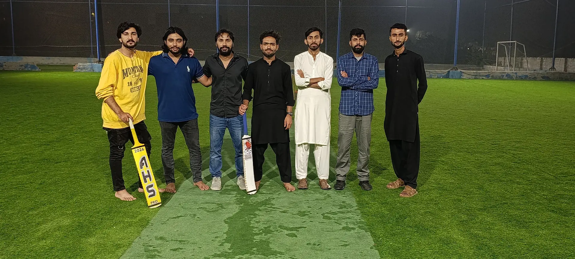 The team lined up on a floodlit cricket pitch