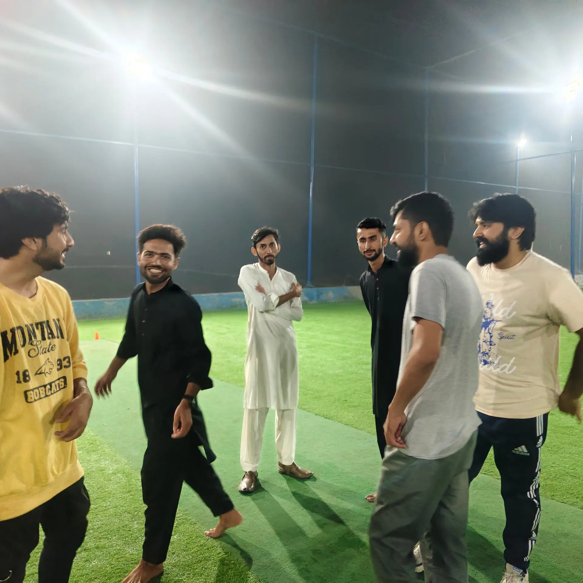 Team members chatting on the cricket pitch at night