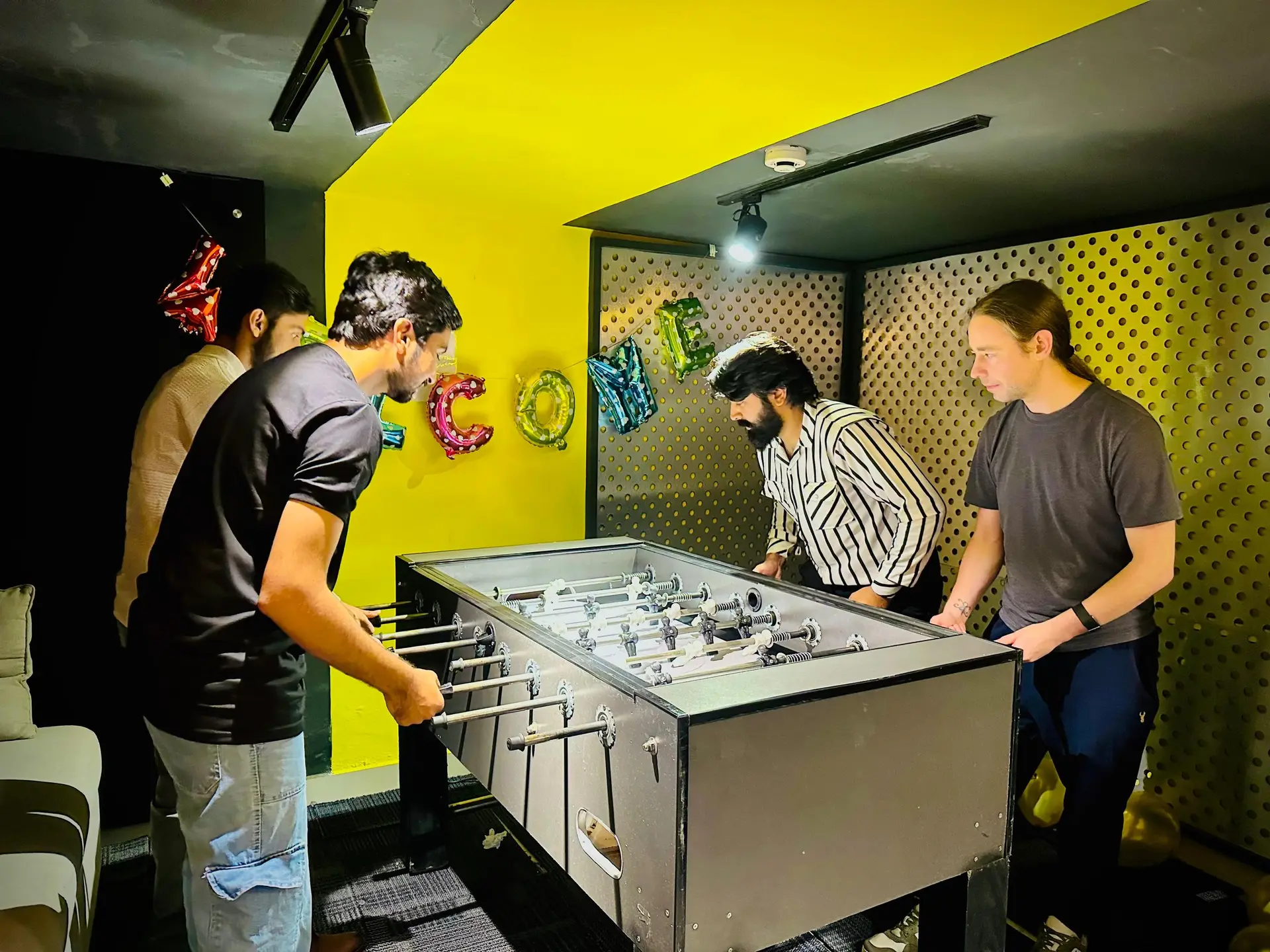 The team welcoming a new joiner at the foosball table