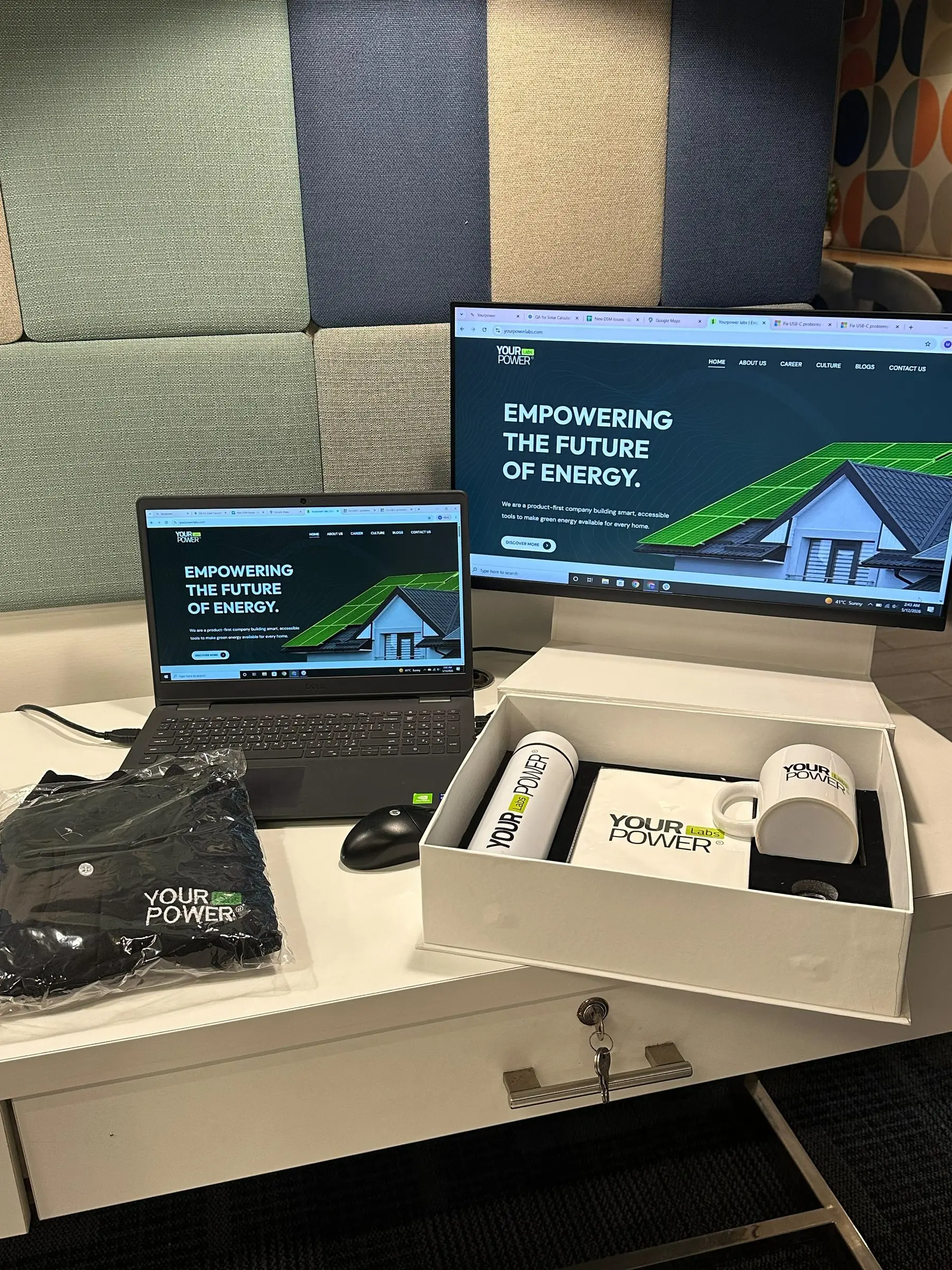 A Labs welcome kit with branded mug, bottle and notebook beside a laptop